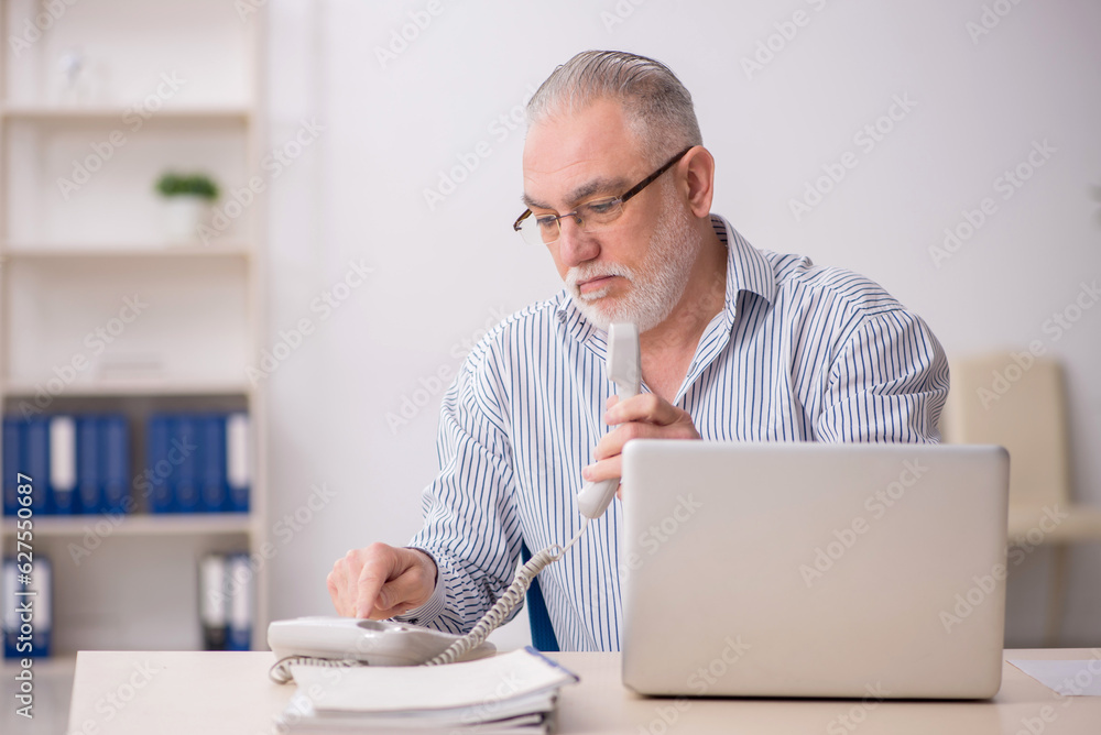 Old male employee working at workplace Old male employee working at workplace