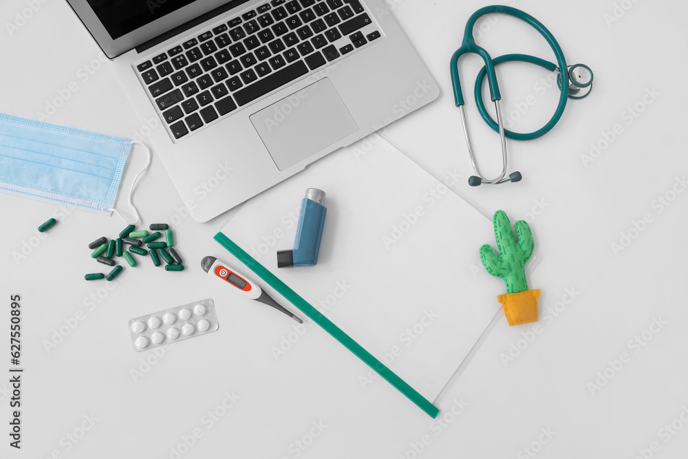 Laptop, stethoscope and pills on white table Laptop, stethoscope and pills on white table