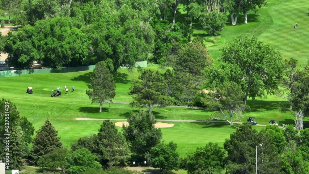 Many people enjoy luxurious country club golf course in USA. Aerial shot of golfers putting and riding in golf carts. Zoom telephoto lens. Many people enjoy luxurious country club golf course in USA. Aerial shot of golfers putting and riding in golf carts. Zoom telephoto lens.