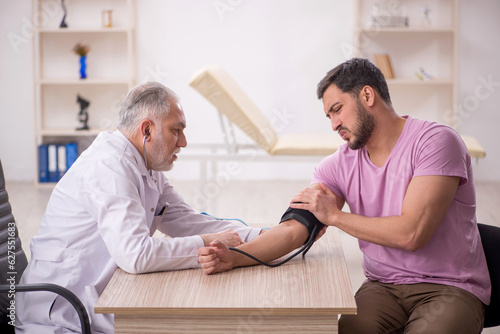 Old male doctor measuring young patient's blood pressure