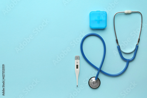 Medical stethoscope and digital thermometer on blue background