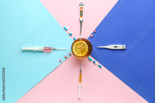 Composition with cup of tea, thermometers, syringes and pills on color background