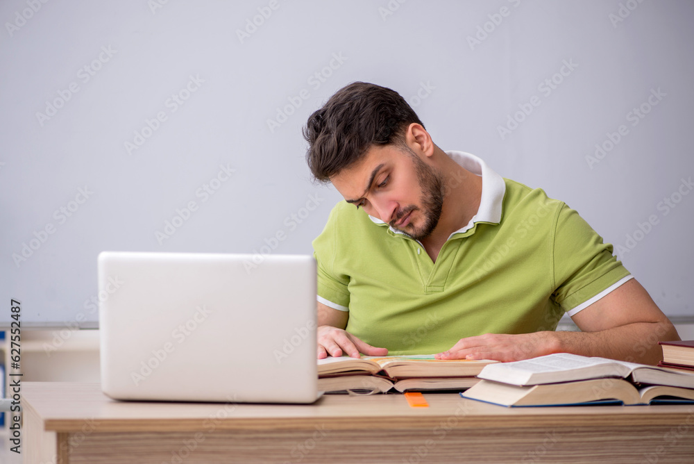 Young male student sitting in front of whiteboard Young male student sitting in front of whiteboard