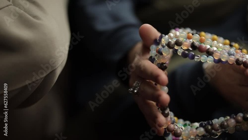 beads jewelry handmade close-up. Handmade jewelry beads close-up in male hands, vertical orientation video. a man holds beads in his hands. Handmade jewelry made of multicolored glass beads.