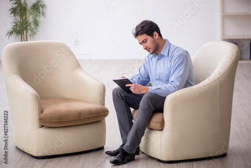Young male psychologist sitting in the room