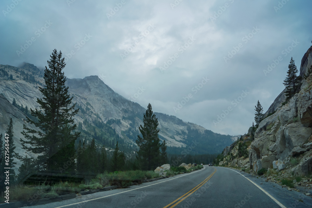 Tioga pass road with scenic view of massive granite rock formation on cloudy mystical day in Yosemite National Park, California, USA. Driving through forest and valleys. Roadtrip, freedom seeking
