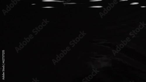 Top view slow motion speed scene of water wave when droplet dropping on a surface of a liquid isolated on black background, a raindrop falling down to the ground in the night