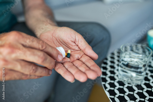 A senior man  feeling stressed and depressed  takes a pill with a glass of water. Depicting the act of self-medication and the impact of antidepressant drugs  use of medicines