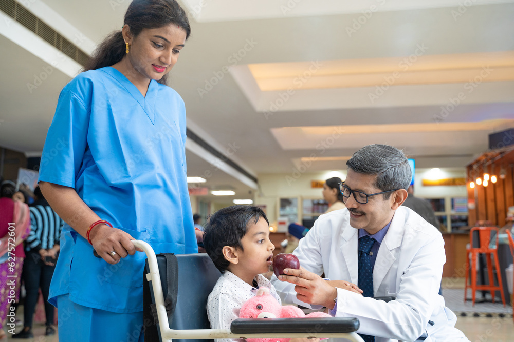 Obraz premium Doctor asking for eating apple to little boy patient