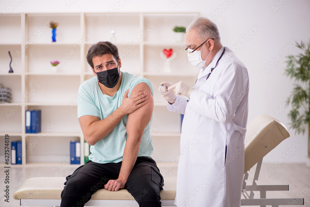 Obraz premium Young male patient visiting old male doctor in vaccination conce