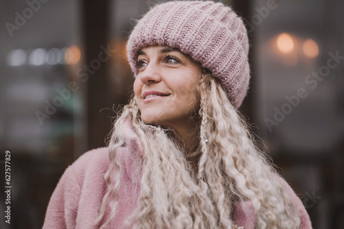Portrait of a mature woman in a fashionable pink knitted hat. Middle aged woman positive and smiling with pigtails
