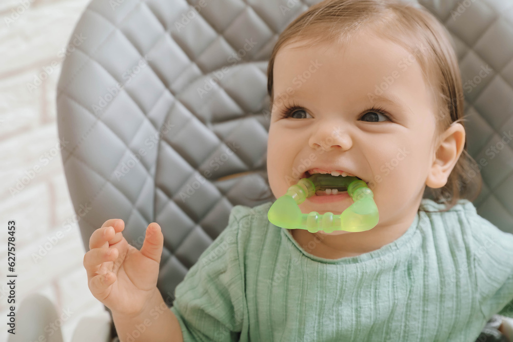 Cute little baby nibbling teether in high chair indoors, closeup Cute little baby nibbling teether in high chair indoors, closeup