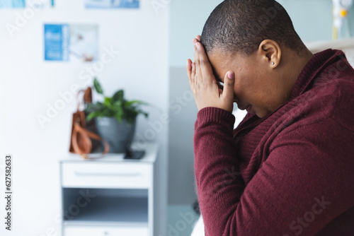 Sad african american female patient sitting on bed and crying in patient room at hospita, copy space