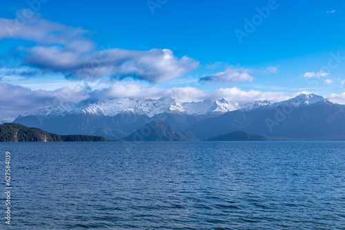 Photograph of a large blue lake and snow-capped mountain range while driving from Te Anau in Fiordland to Manapouri on the South Island of New Zealand © Phillip