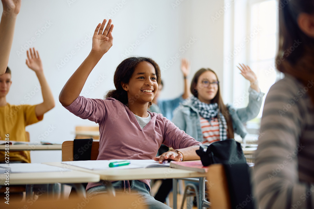 Happy black teenage girl and her classmates raising hands to answer question during class at high school. Happy black teenage girl and her classmates raising hands to answer question during class at high school.