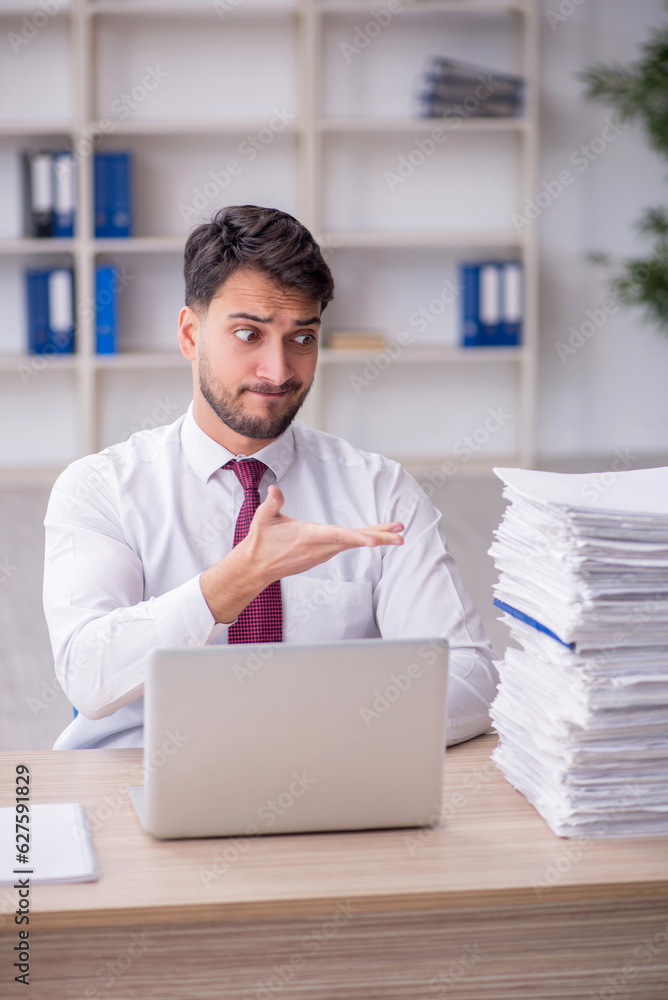 Naklejka premium Young male employee and too much work in the office