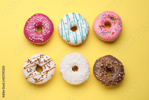 Tasty glazed donuts on yellow background, flat lay