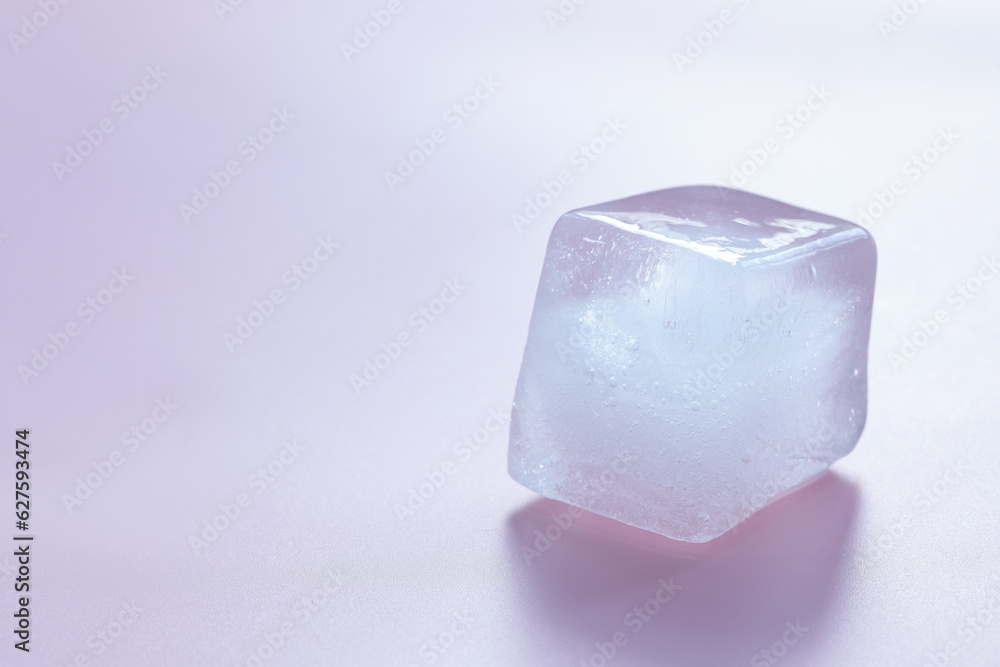 Crystal clear ice cube on light pink background, space for text Crystal clear ice cube on light pink background, space for text