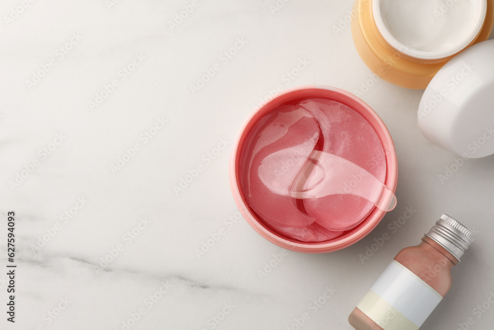 Jar of under eye patches with spoon and cosmetic products on white marble table, flat lay. Space for text Jar of under eye patches with spoon and cosmetic products on white marble table, flat lay. Space for text