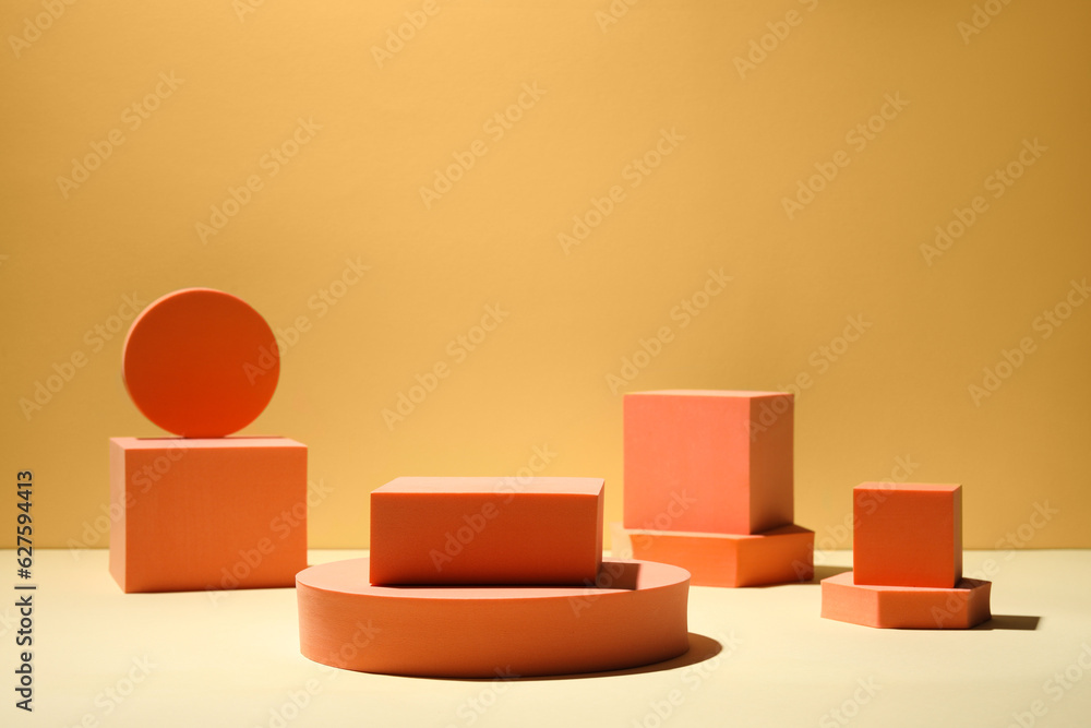 Many orange geometric figures on table against yellow background, space for text. Stylish presentation for product Many orange geometric figures on table against yellow background, space for text. Stylish presentation for product