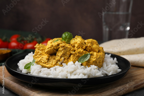 Delicious rice and chicken with curry sauce on wooden board, closeup