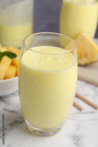 Tasty pineapple smoothie on white marble table, closeup