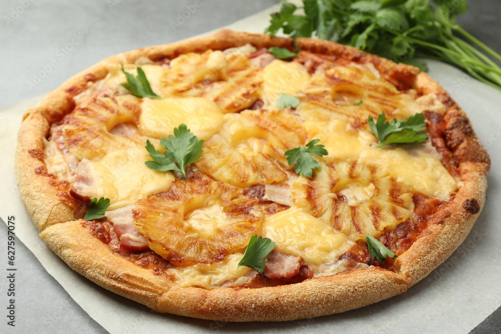 Delicious pineapple pizza with parsley on gray table, closeup