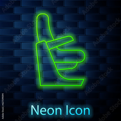 Glowing neon line Airplane seat icon isolated on brick wall background. Vector