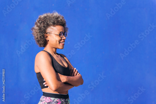 Profile of a strong african american sportswoman in a blue background outdoors in a sunny day, concept of real people and sporty lifestyle, copy space for text