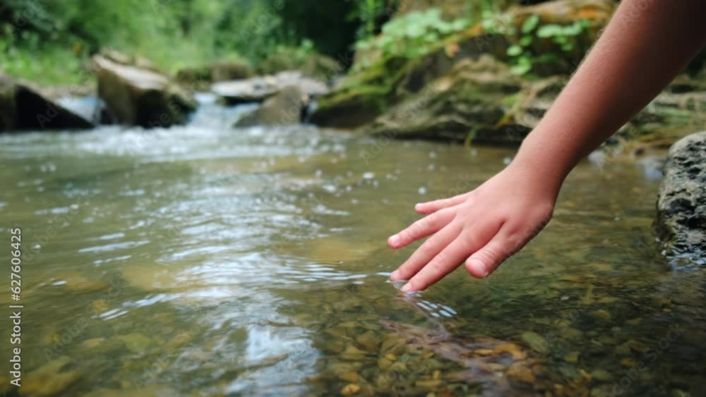 Close up of child hand touching mountain water at calm summertime. Holistic and environment conscious lifestyle concept. Clear and clean water in nature. Conservation of natural resources Close up of child hand touching mountain water at calm summertime. Holistic and environment conscious lifestyle concept. Clear and clean water in nature. Conservation of natural resources