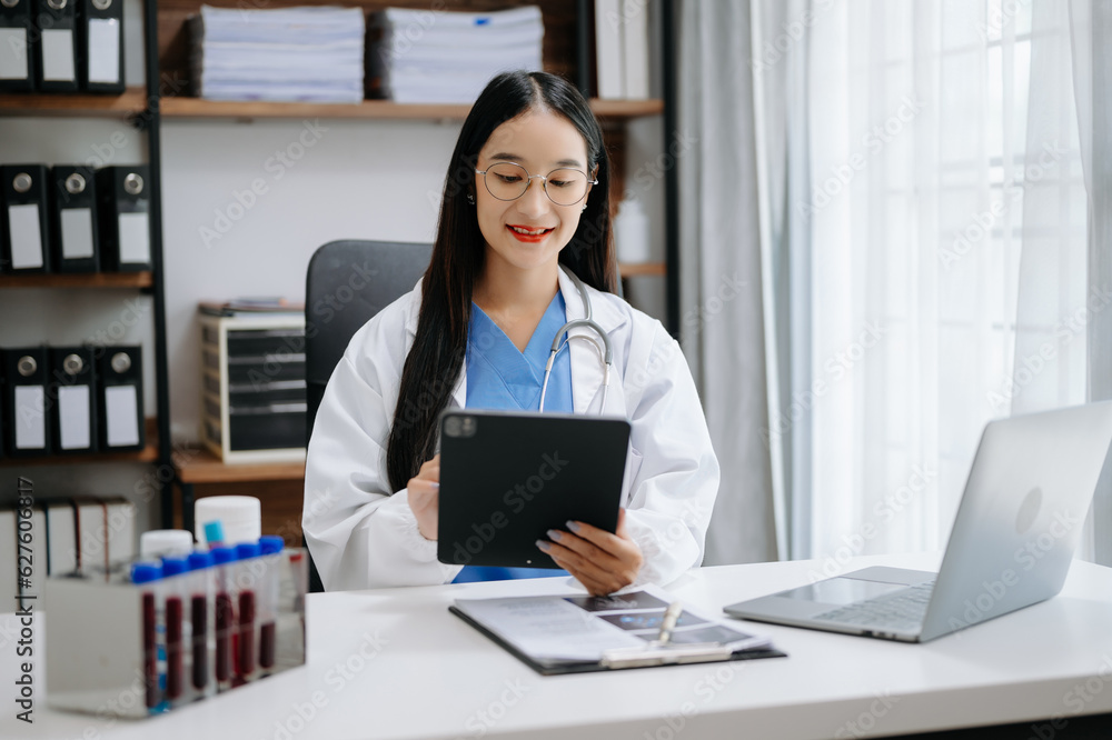 Asian smiling doctor or consultant sitting at a desk his neck looking at the camera Asian smiling doctor or consultant sitting at a desk his neck looking at the camera
