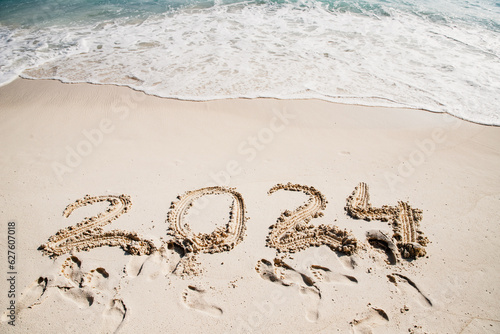 2024 written in white sand on tropical beach, happy New Year