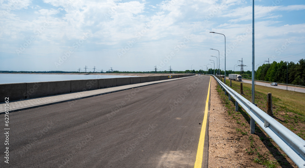Asphalt road next to the concrete bank of the dam