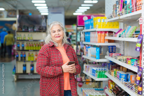 Senior indian woman standing at grocery shop.
