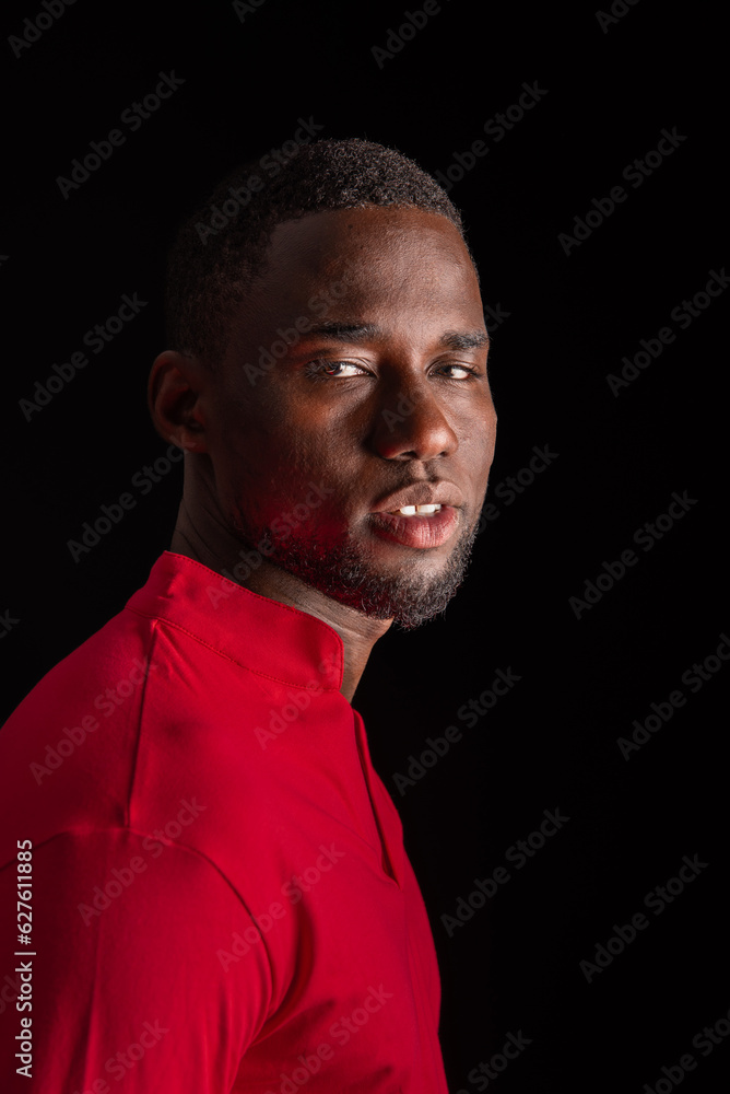 Serious African American man in casual outfit against black background