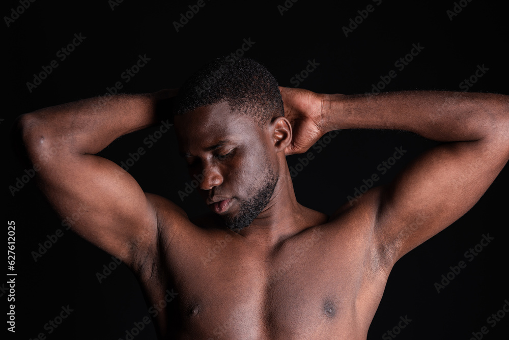 Young black man with hands behind head and with eyes closed showing abs in light Young black man with hands behind head and with eyes closed showing abs in light