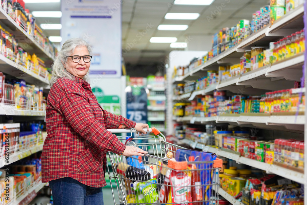 senior indian woman purchasing at grocery shop.