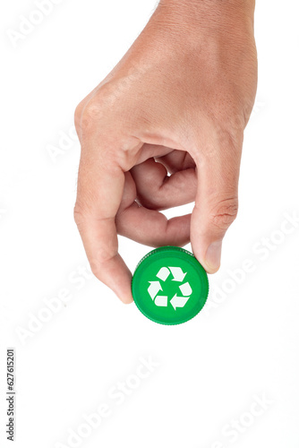 Hand holding green recycling plastic cap on white background. Recycling concept