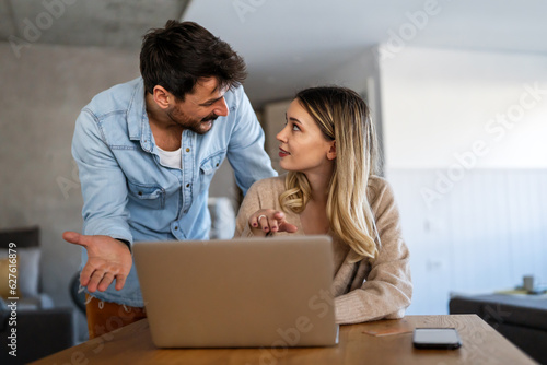 Couple of young designers working at modern home office, two coworkers discussing fun project