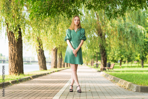 Portrait of a girl in a green dress on a walk on a sunny summer day in the park.