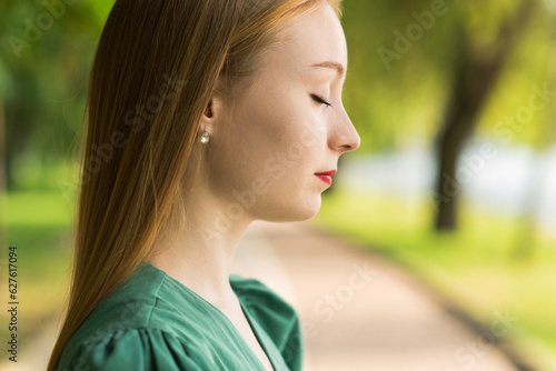 Portrait of a girl in a green dress on a walk on a sunny summer day in the park. © Павел Костенко