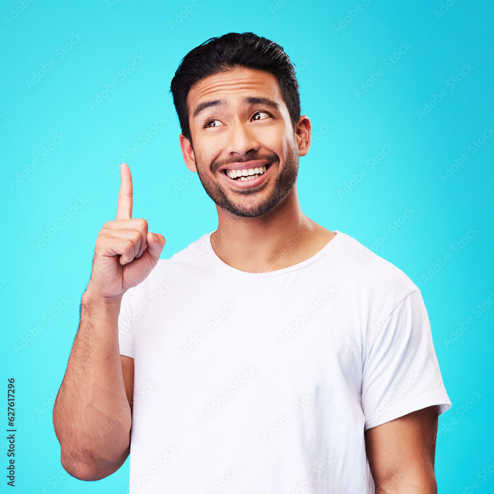 Fototapeta premium Mockup, pointing up and man with a smile, thinking and solution against a blue studio background. Male person, decision and model with hand gesture, opportunity or option with sign, choice or showing
