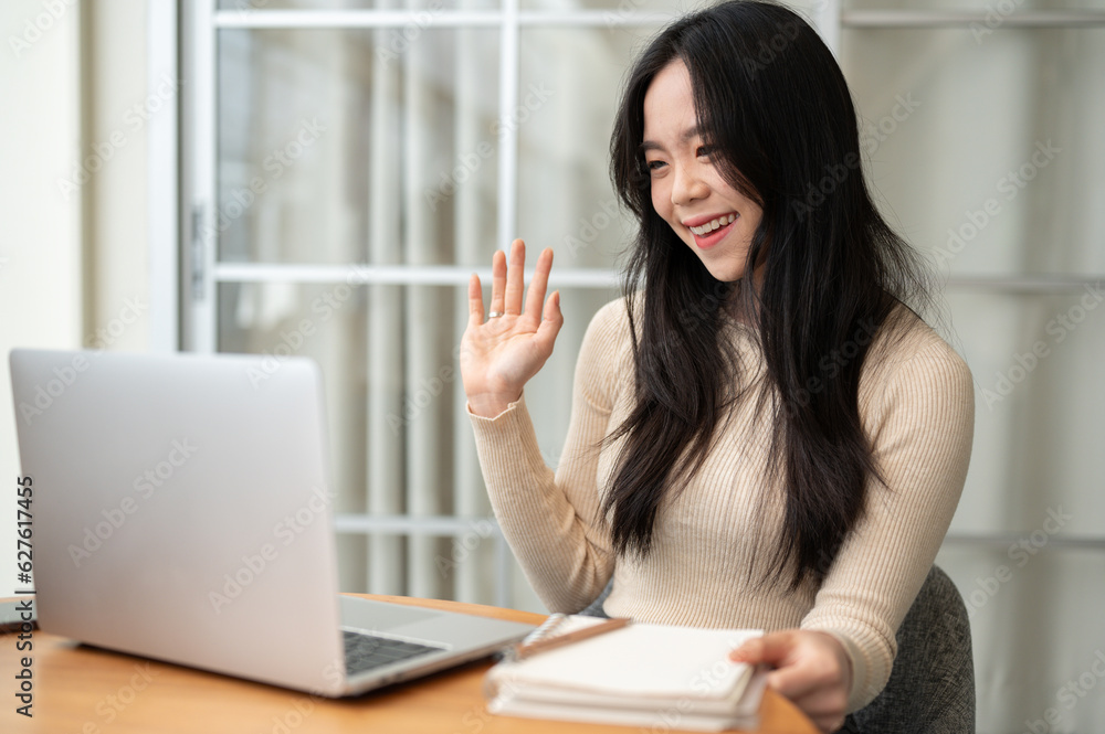 A happy Asian female college student studying online in an online class while staying at home. A happy Asian female college student studying online in an online class while staying at home.