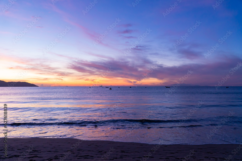 Seascape at dawn with boats and colorful sky.