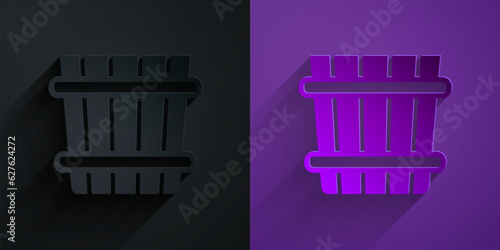 Paper cut Sauna bucket icon isolated on black on purple background. Paper art style. Vector