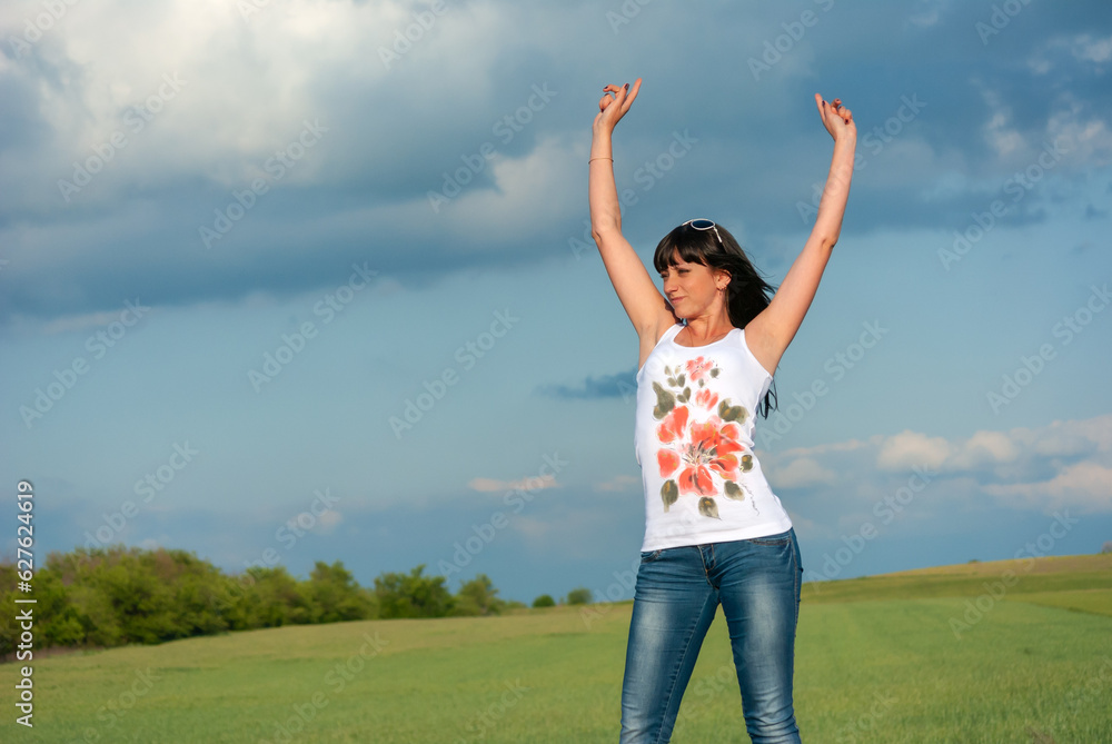 A beautiful brunette with big breasts stands against the blue sky in a white T-shirt A beautiful brunette with big breasts stands against the blue sky in a white T-shirt