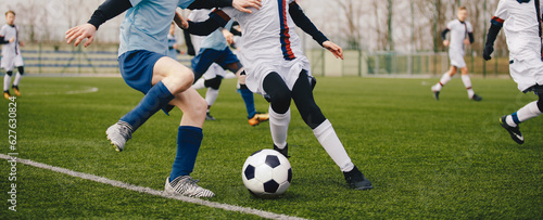 Legs of two young football players on a match. Two soccer players running and kicking a soccer ball.  European football youth player legs in action. Anonymous footballers compete in a football duel © matimix