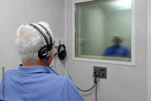 Audiologist woman doing the hearing exam to a mixed race man patient using an audiometer in a special audio room. Audiometric testing. Hearing loss treatment. photo