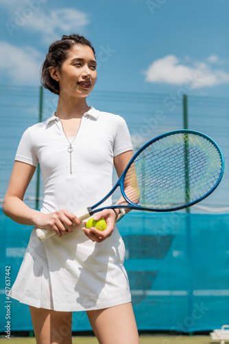 happy woman in active wear holding tennis racquet and ball, player on court, sport and motivation © LIGHTFIELD STUDIOS