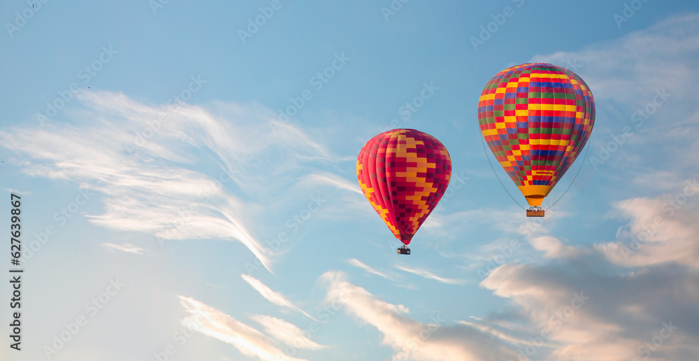 Fototapeta premium Colorful hot air balloon flying over clouds at sunset